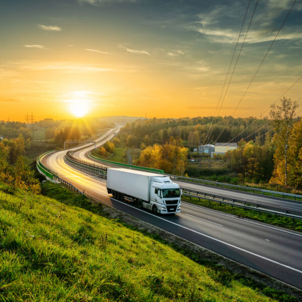 Weißer LKW fährt auf der Autobahn durch bewaldete Landschaft, bei Sonnenuntergang. #daskannkunststoff